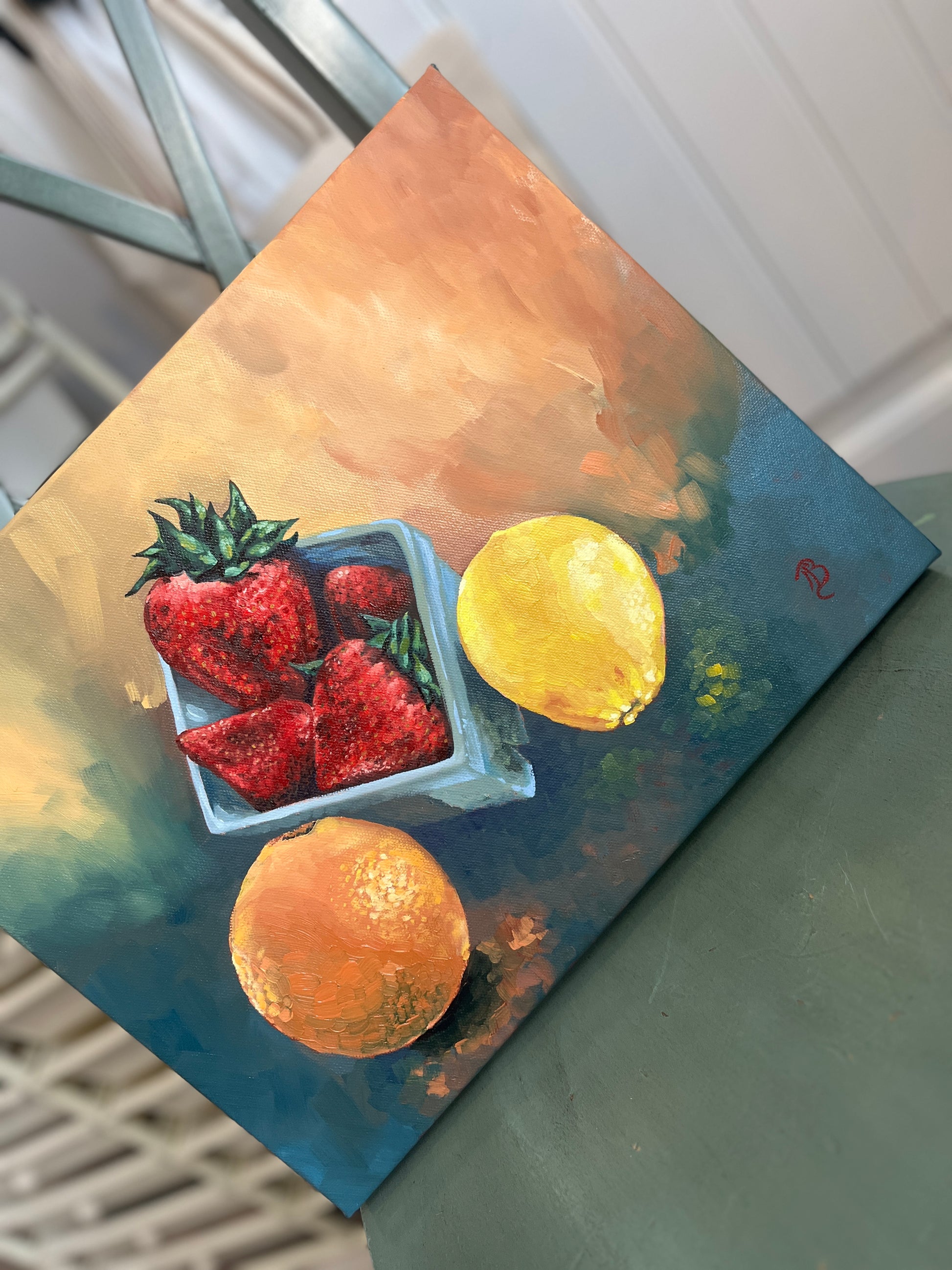 Still life painting of strawberries, an orange, and a lemon on a textured orange and blue surface