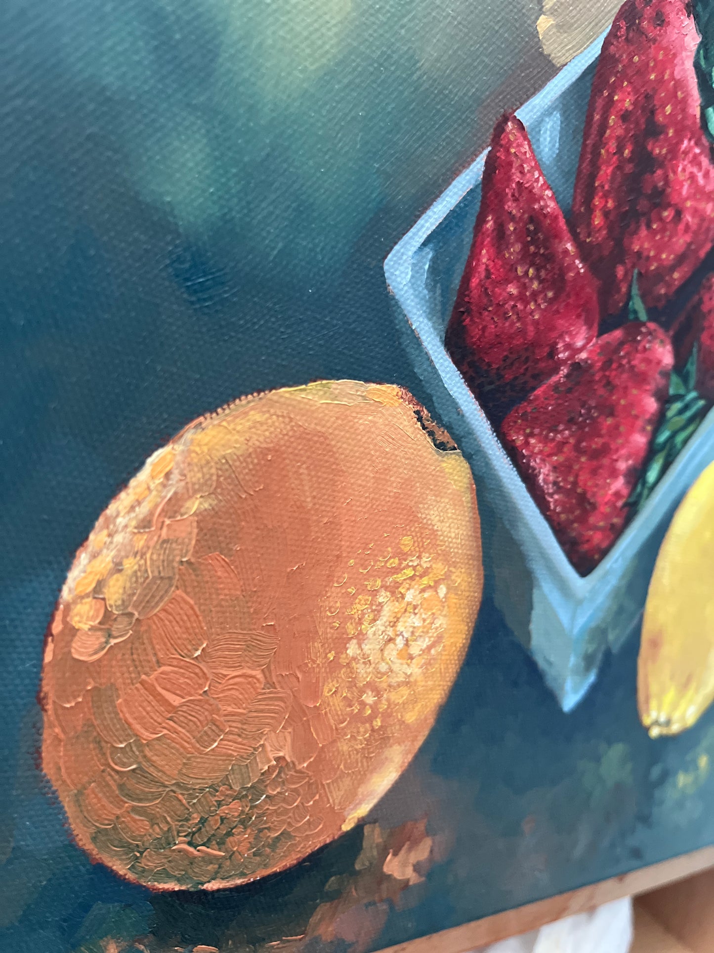 Close up sideview of original still life painting of strawberries, an orange, and a lemon