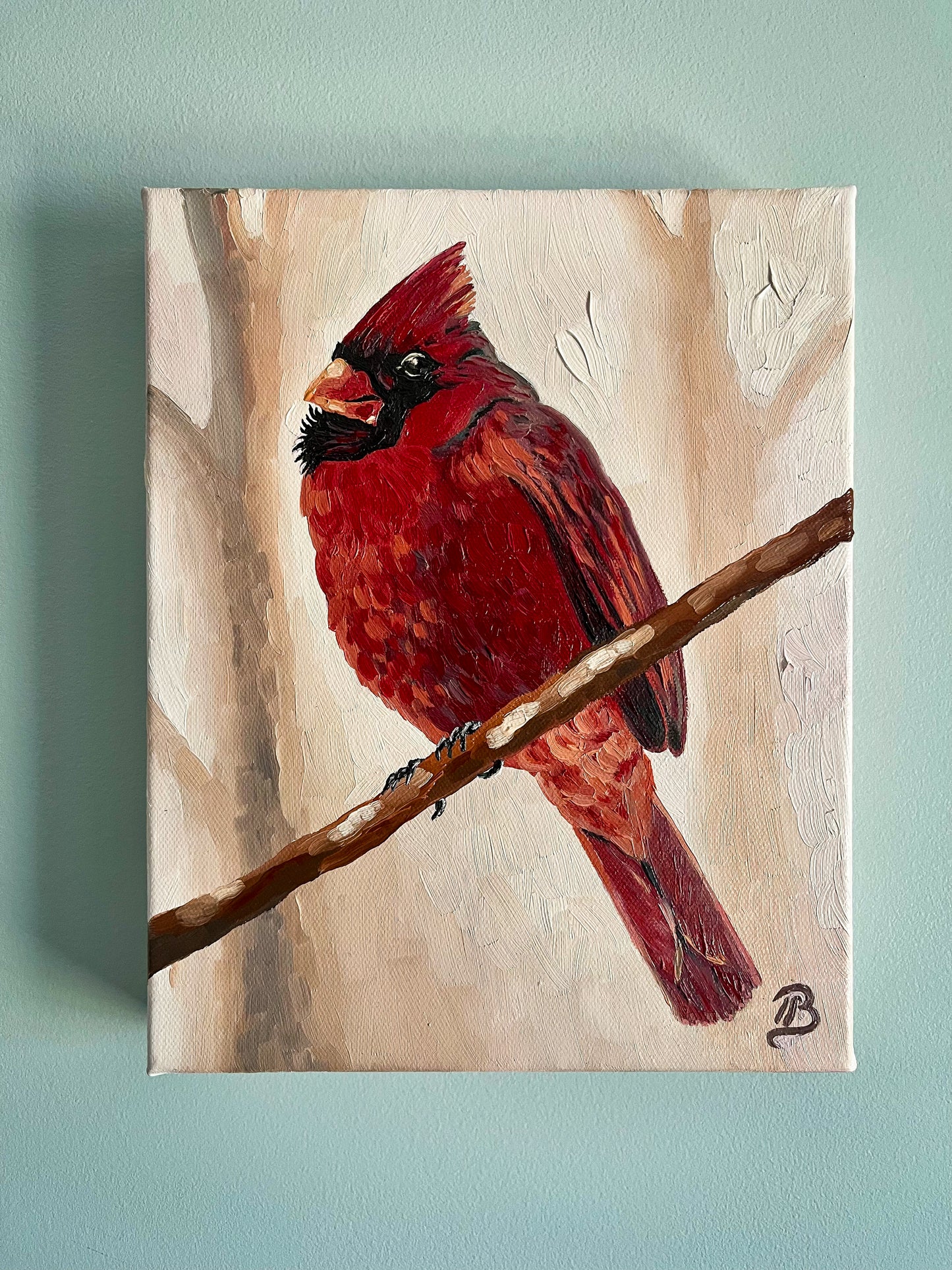 Painting of a red cardinal bird on a branch with a light pink background