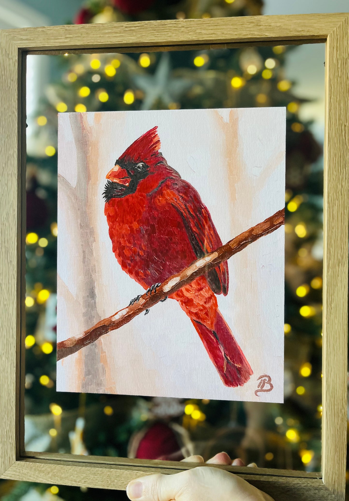 Framed fine art print of a red cardinal perched on a branch with the glow of Christmas tree lights in the background
