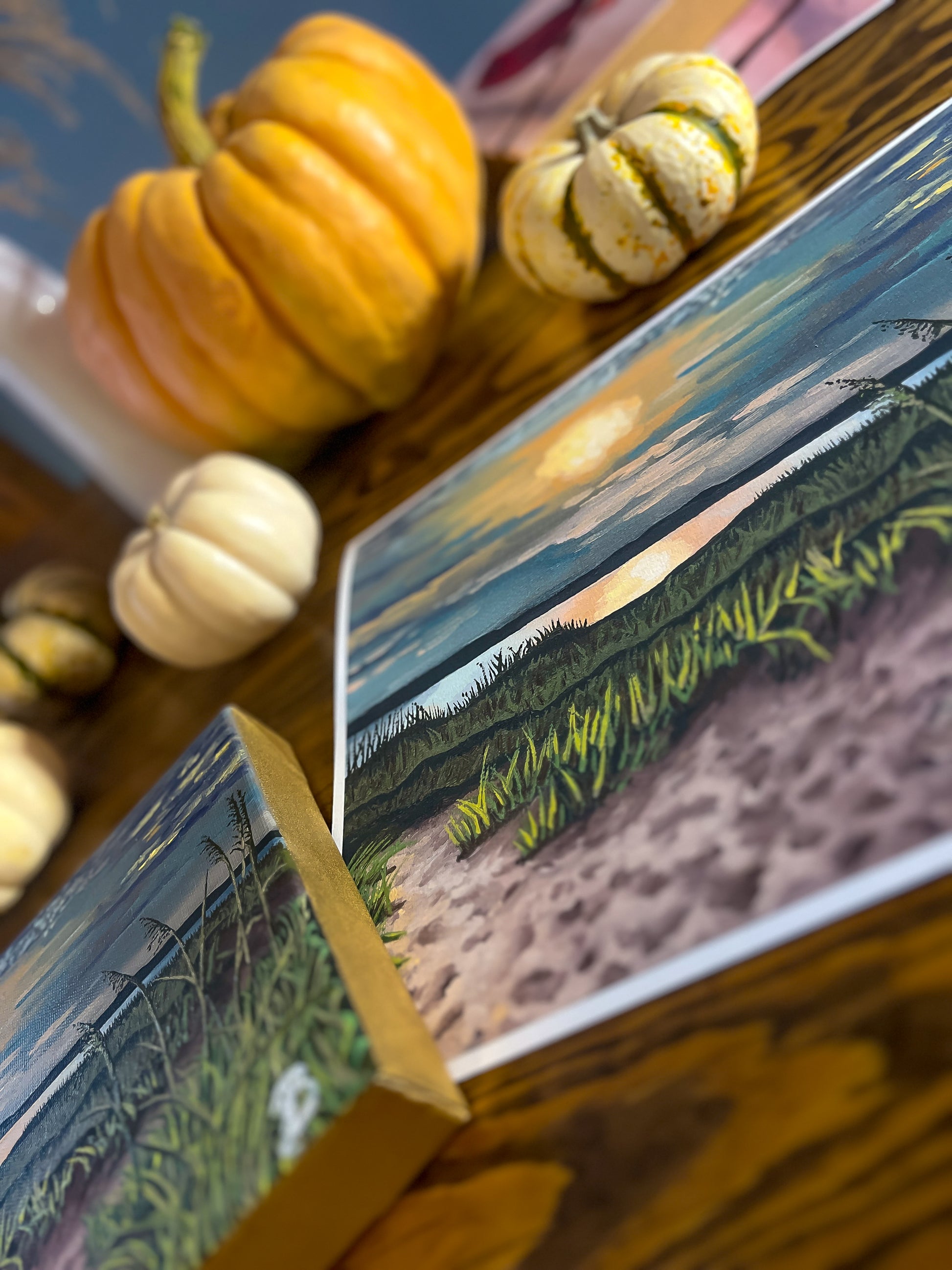 Close-up of a seascape sunset painting with pumpkins on the table in the background