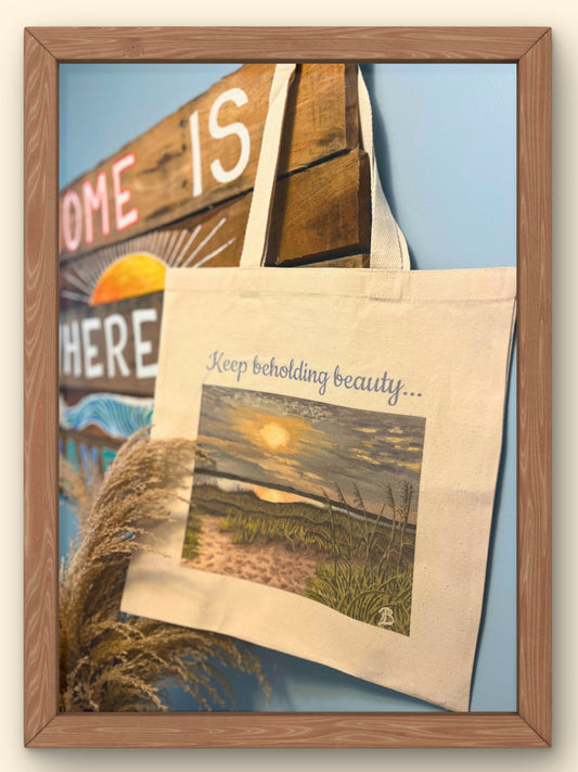 Tote bag with scenic design and text 'Keep beholding beauty' in a wooden frame.