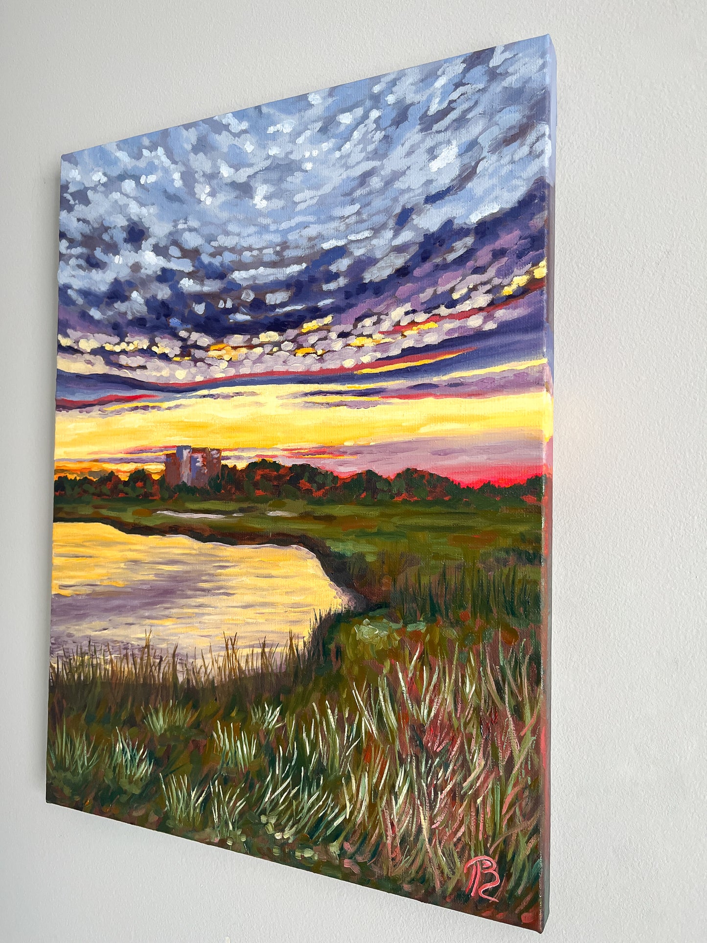 Painting of a sunset over the intracoastal waterway and marsh with building in distance.