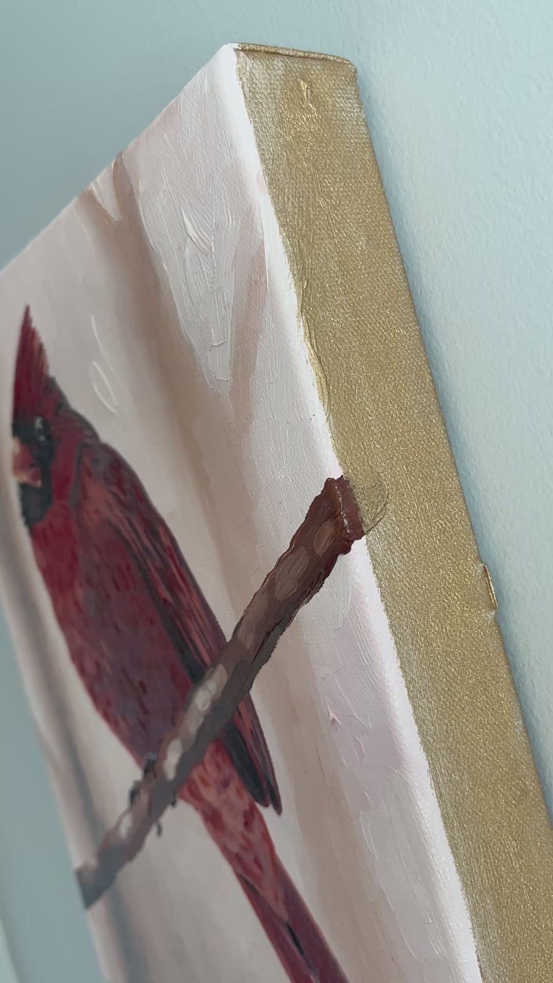 Video close-up of red cardinal painting with gold painted canvas edges.
